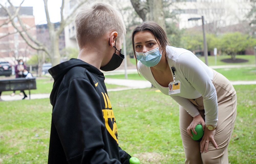 grad clinician playing baseball with child client receiving speech therapy