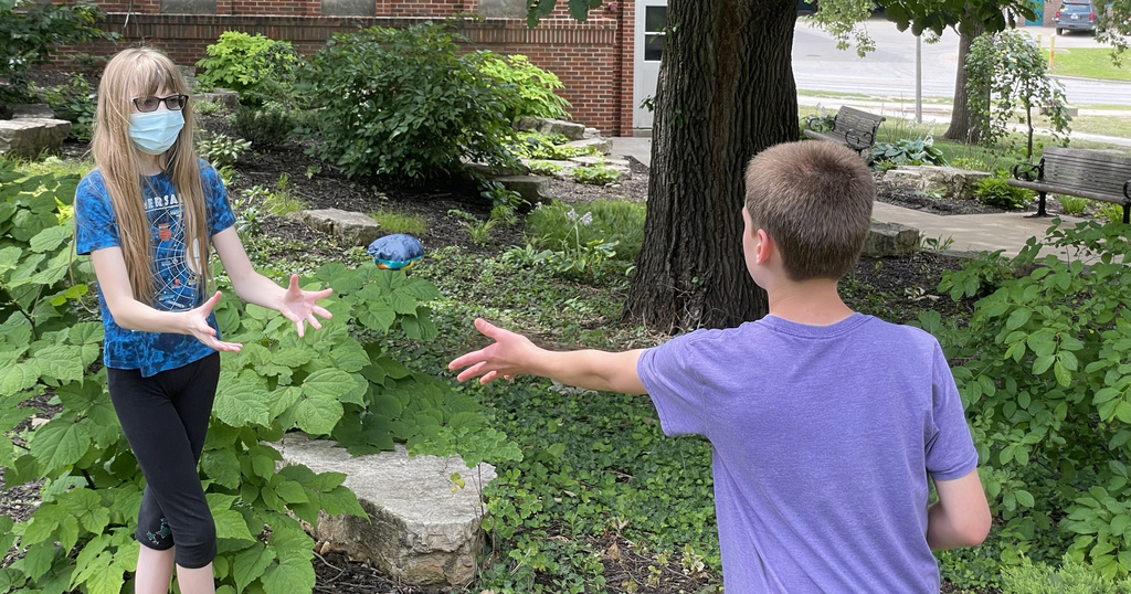 children tossing water balloon outdoors