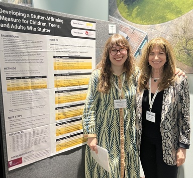 Naomi Rodgers and Vivian Sisskin stand in front of their poster collaboration.