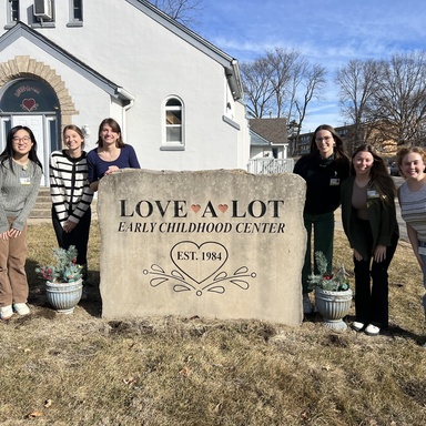 A group of graduate students standing in front of a local preschool