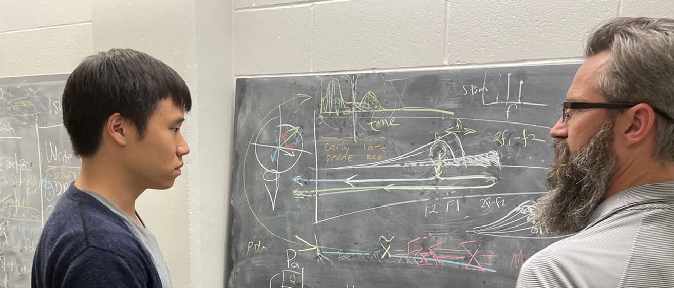 phd student with mentor at chalkboard