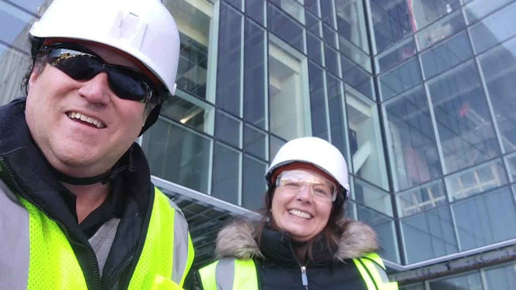 Eric Hunter and Lucie Hulse wearing hardhats standing outside the new Health Sciences Academic Building construction site