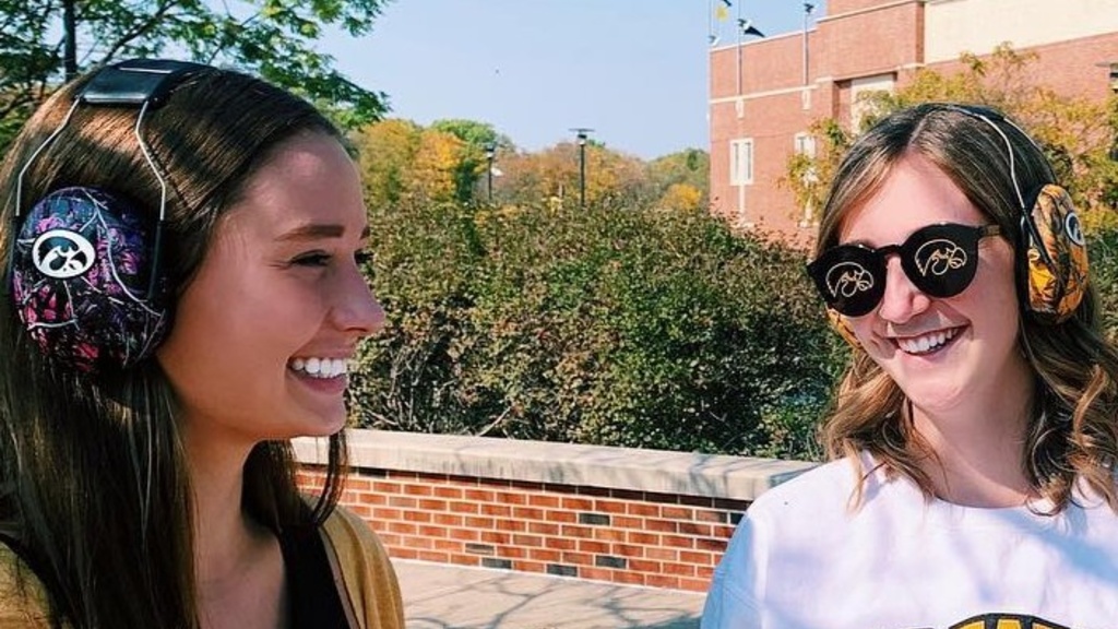 Two female students wearing Hawkeye headphones